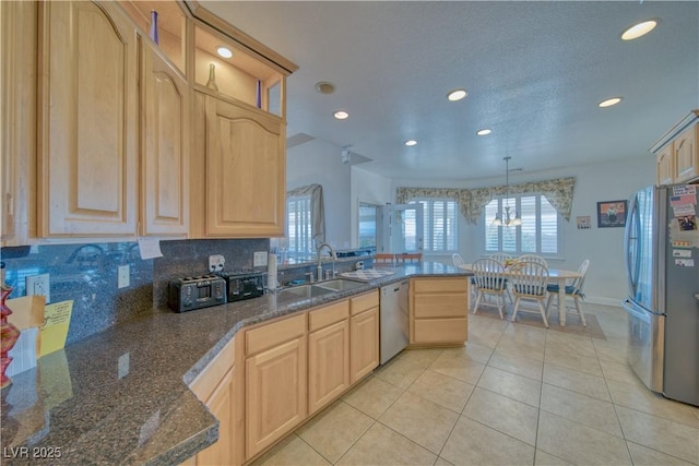 kitchen featuring a peninsula, appliances with stainless steel finishes, light brown cabinets, and a sink