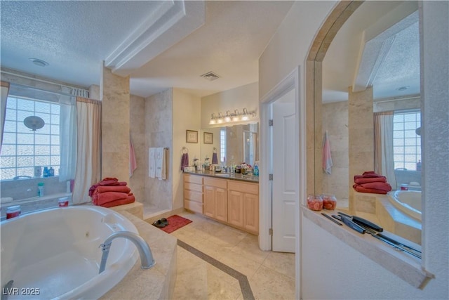 bathroom with vanity, a textured ceiling, visible vents, tile patterned floors, and a jetted tub