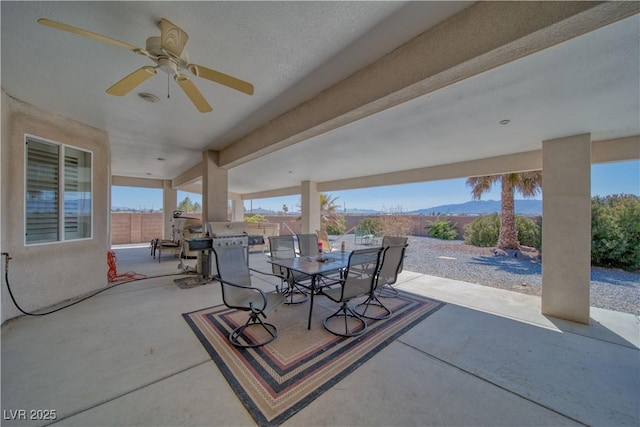 view of patio with a fenced backyard, a ceiling fan, and outdoor dining space