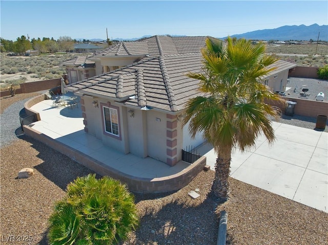 view of property exterior featuring a patio area, stucco siding, a tiled roof, and a mountain view