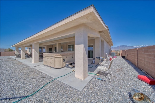 rear view of house featuring a fenced backyard, a patio area, stucco siding, and a mountain view