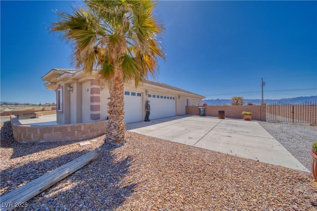 view of side of home featuring stucco siding, driveway, fence, and a garage