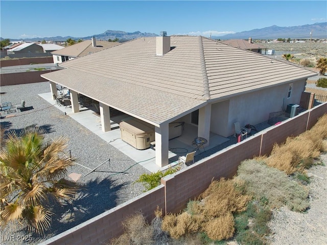 exterior space with a chimney, a patio area, a mountain view, and fence