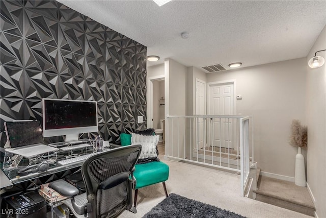 home office with a textured ceiling, visible vents, baseboards, and carpet floors