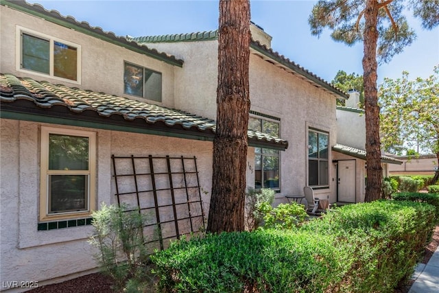 back of house featuring a tiled roof and stucco siding