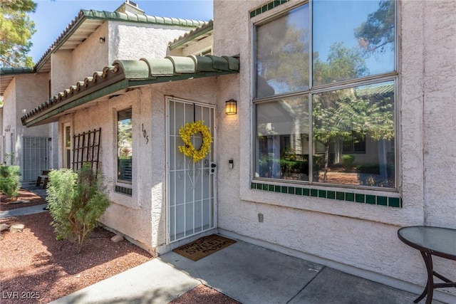 property entrance featuring stucco siding and a tiled roof