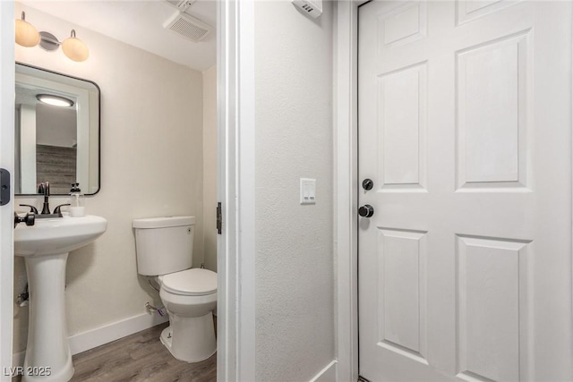 bathroom featuring baseboards, visible vents, toilet, and wood finished floors