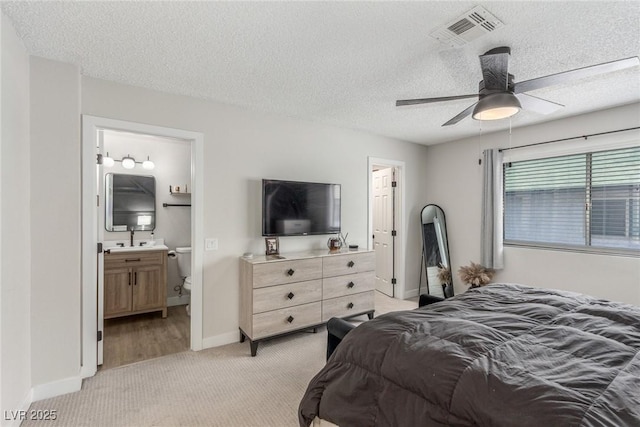bedroom featuring a textured ceiling, baseboards, visible vents, and light colored carpet