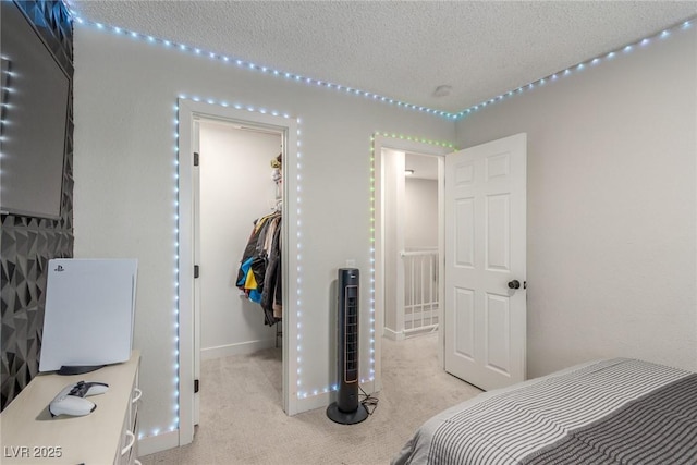 carpeted bedroom with baseboards, a spacious closet, a closet, and a textured ceiling
