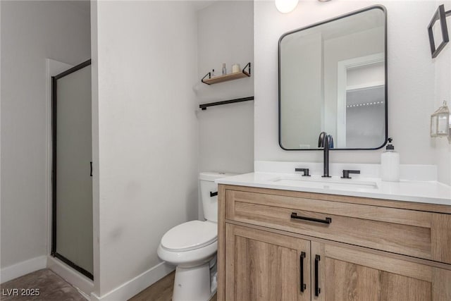 bathroom featuring vanity, toilet, baseboards, and a shower stall