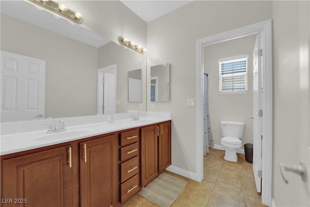 full bath featuring toilet, tile patterned floors, double vanity, and a sink