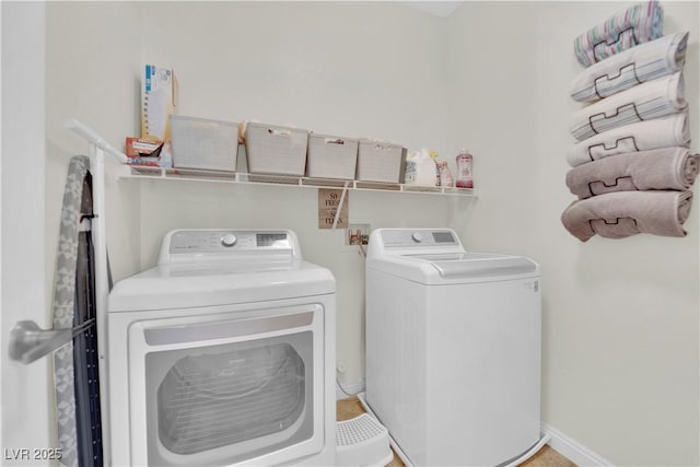 washroom featuring washing machine and clothes dryer, laundry area, and baseboards