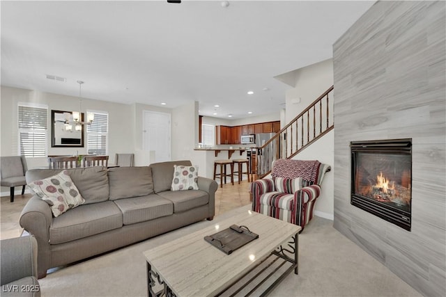 living area featuring recessed lighting, stairway, a tiled fireplace, a chandelier, and light carpet