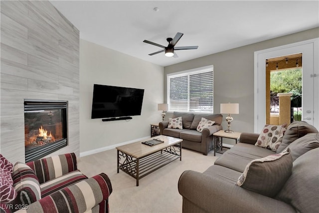 carpeted living room with a tile fireplace, baseboards, and ceiling fan