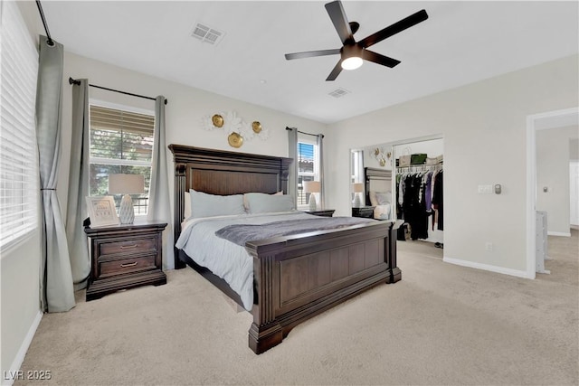 bedroom featuring baseboards, light carpet, visible vents, and a walk in closet