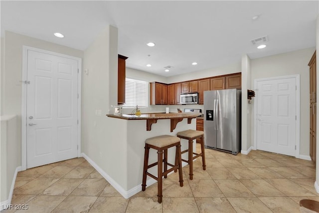 kitchen featuring a peninsula, stainless steel appliances, visible vents, a breakfast bar area, and recessed lighting