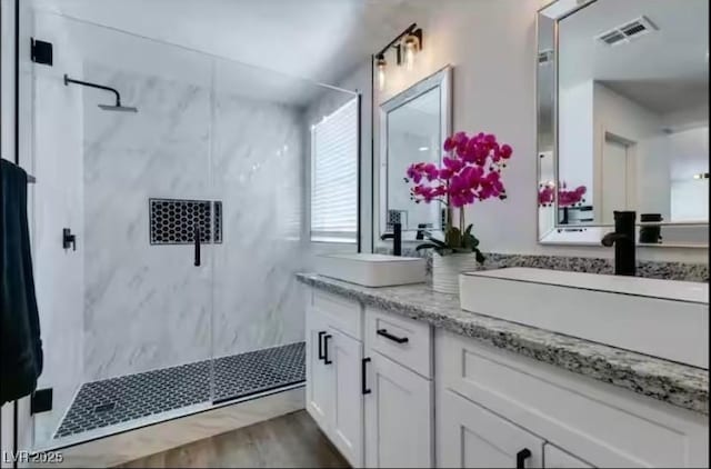 6736 Quinella Dr, Las Vegas, NV 89103 - full bath featuring double vanity, a marble finish shower, wood finished floors, a sink, and visible vents