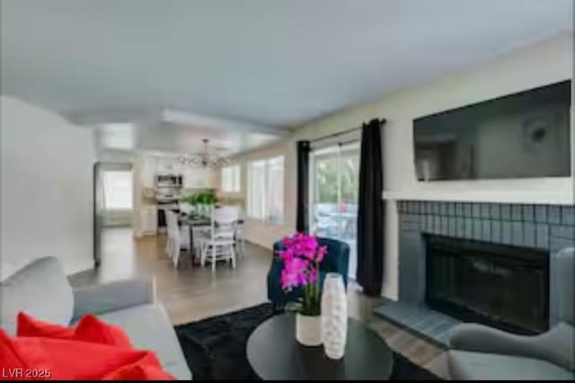 6736 Quinella Dr, Las Vegas, NV 89103 - living area with a notable chandelier, a fireplace, plenty of natural light, and wood finished floors