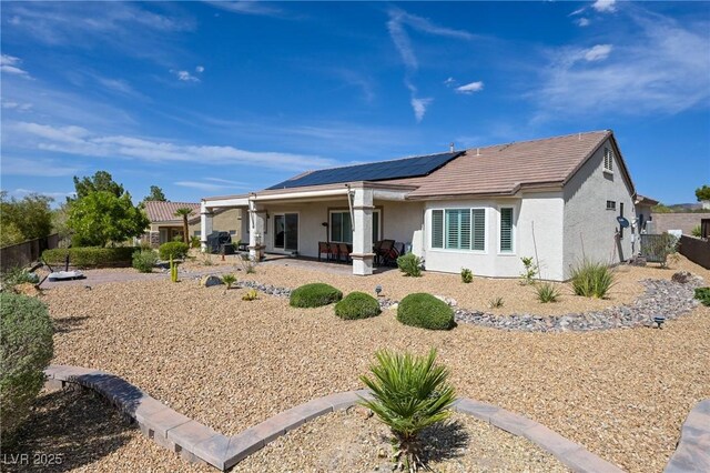 1613 Williamsport St, Henderson, NV 89052 - rear view of house featuring roof mounted solar panels, stucco siding, fence, a tiled roof, and a patio