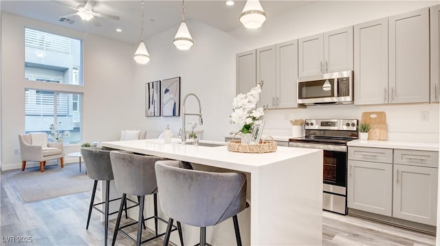 1157 Blossom Point St, Las Vegas, NV 89135 - kitchen with a sink, appliances with stainless steel finishes, a towering ceiling, light countertops, and light wood-style floors