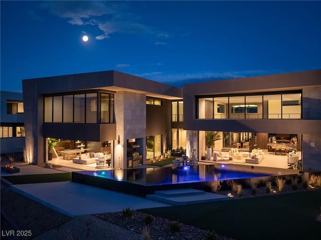 12 Chisel Crest Ct, Henderson, NV 89012 - back of house at night featuring an outdoor hangout area, a patio, an outdoor kitchen, and an infinity pool