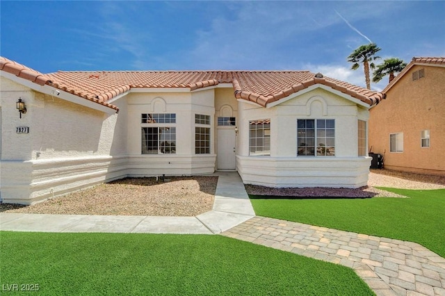 mediterranean / spanish-style home with stucco siding, a tile roof, and a front yard