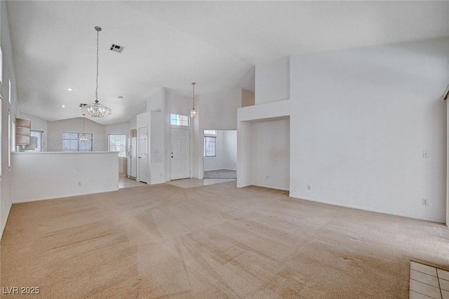 unfurnished living room featuring light colored carpet, a notable chandelier, high vaulted ceiling, and visible vents