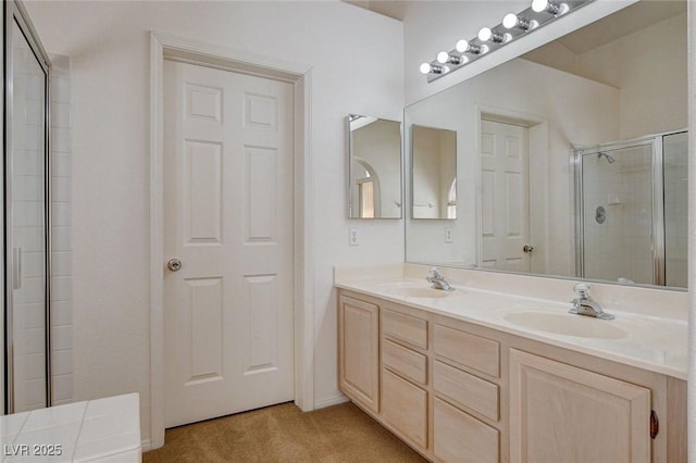 full bathroom with a stall shower, double vanity, and a sink