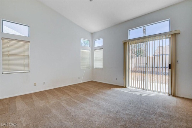 carpeted empty room featuring baseboards and high vaulted ceiling