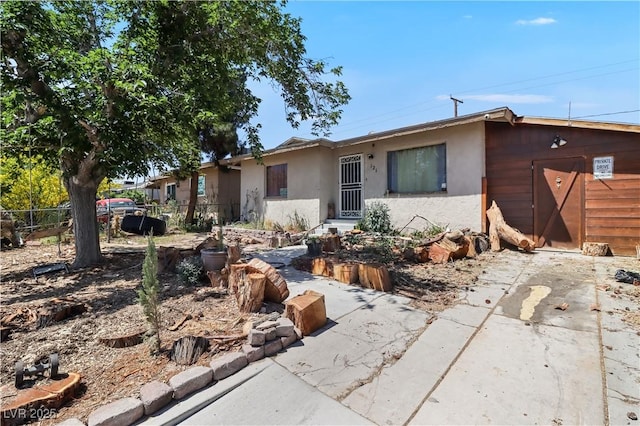 ranch-style house featuring stucco siding and fence