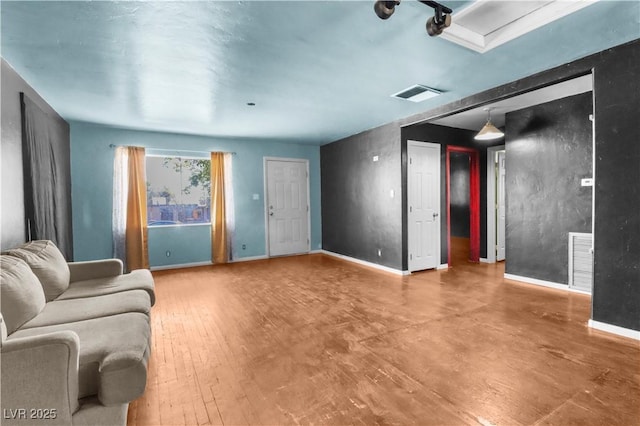 living area featuring wood finished floors, visible vents, and baseboards