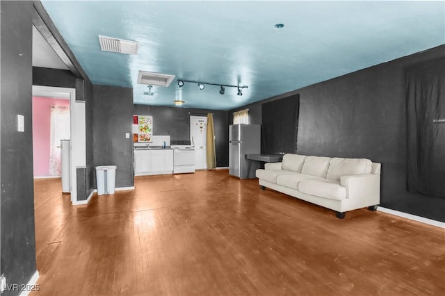 living area featuring track lighting, visible vents, wood finished floors, and baseboards