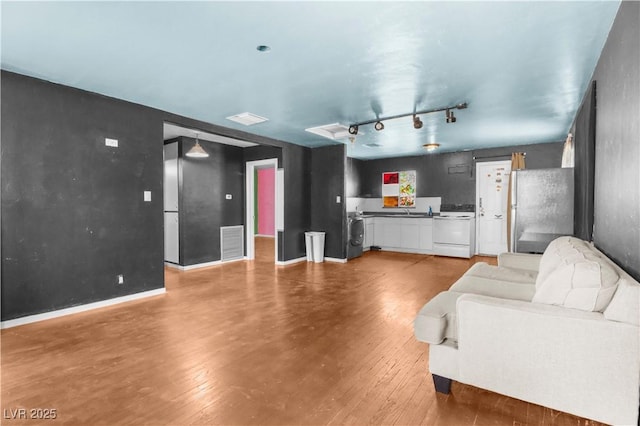 living room featuring washer / dryer, visible vents, wood-type flooring, and track lighting