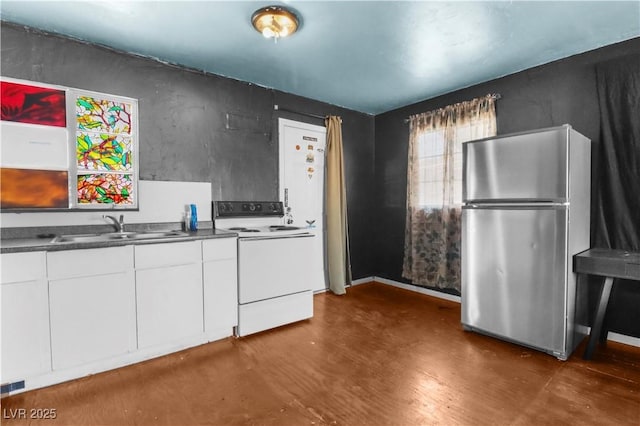 kitchen featuring freestanding refrigerator, white cabinets, a sink, and electric range