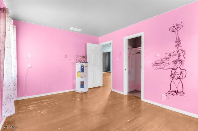 unfurnished bedroom with electric water heater, wood finished floors, visible vents, and baseboards