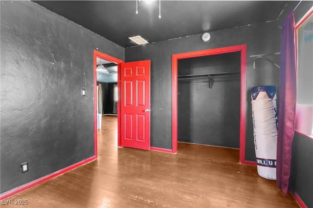 unfurnished bedroom featuring a closet, visible vents, and wood finished floors