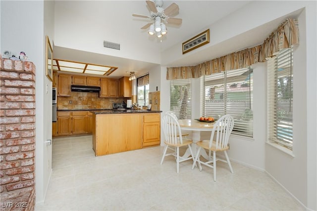 1528 Tonada Way, Las Vegas, NV 89117 - kitchen with under cabinet range hood, dark countertops, a peninsula, decorative backsplash, and ceiling fan