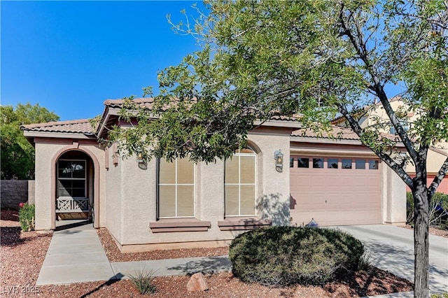 view of front of home with concrete driveway, stucco siding, a tile roof, and a garage