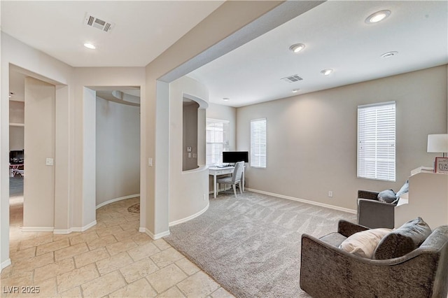 living area featuring baseboards, light colored carpet, stone tile floors, recessed lighting, and an office area
