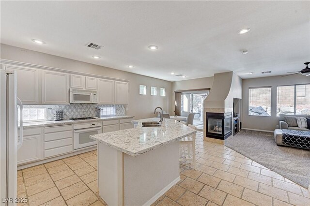 kitchen with white appliances, open floor plan, a sink, decorative backsplash, and ceiling fan