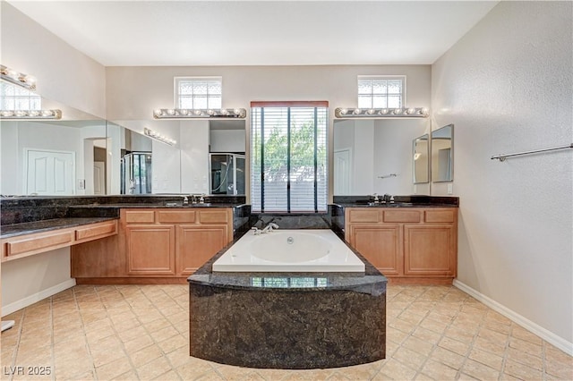 full bathroom with two vanities, a garden tub, and baseboards