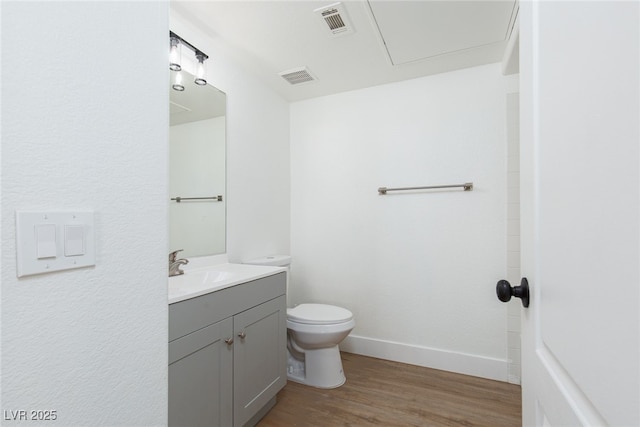 bathroom with wood finished floors, toilet, vanity, and baseboards