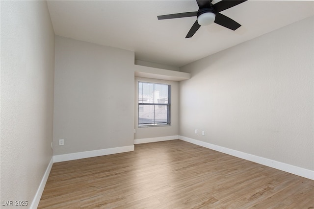spare room featuring light wood finished floors, ceiling fan, and baseboards