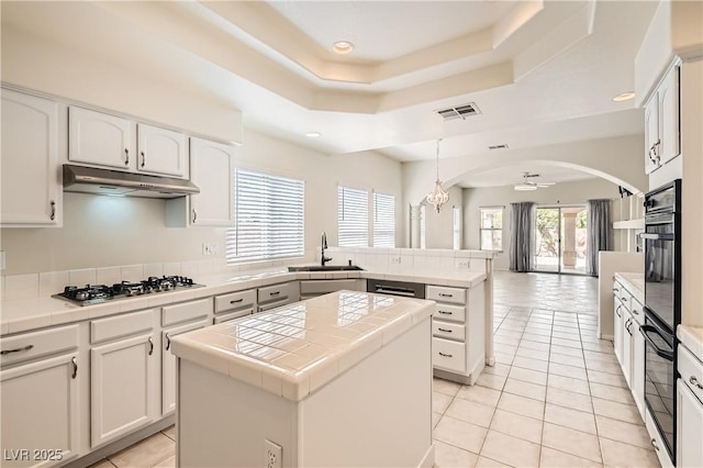 427 Rhythm St, Henderson, NV 89074 - kitchen with a peninsula, a sink, under cabinet range hood, tile countertops, and stainless steel gas cooktop