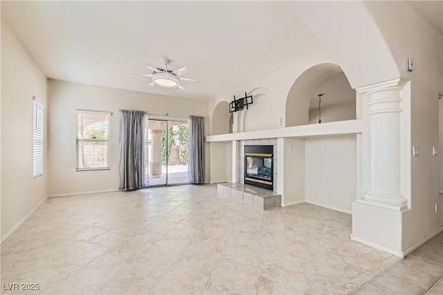427 Rhythm St, Henderson, NV 89074 - unfurnished living room with ceiling fan, a tile fireplace, light tile patterned floors, and decorative columns