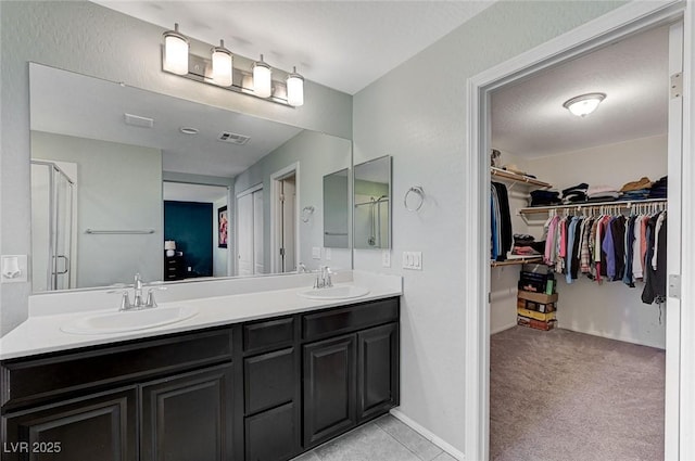 full bathroom with a sink, double vanity, a stall shower, and visible vents