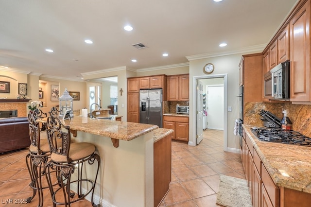 10314 Premia Pl, Las Vegas, NV 89135 - kitchen featuring visible vents, a sink, a kitchen bar, decorative backsplash, and stainless steel appliances