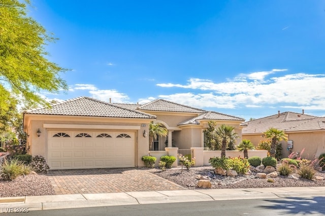 10314 Premia Pl, Las Vegas, NV 89135 - view of front facade featuring a tiled roof, fence, decorative driveway, an attached garage, and stucco siding