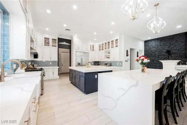 kitchen with appliances with stainless steel finishes, a large island, backsplash, a chandelier, and recessed lighting