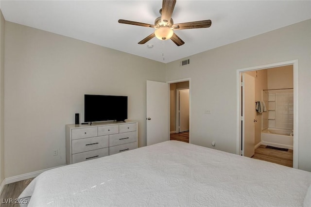 bedroom featuring wood finished floors, ensuite bath, visible vents, ceiling fan, and baseboards